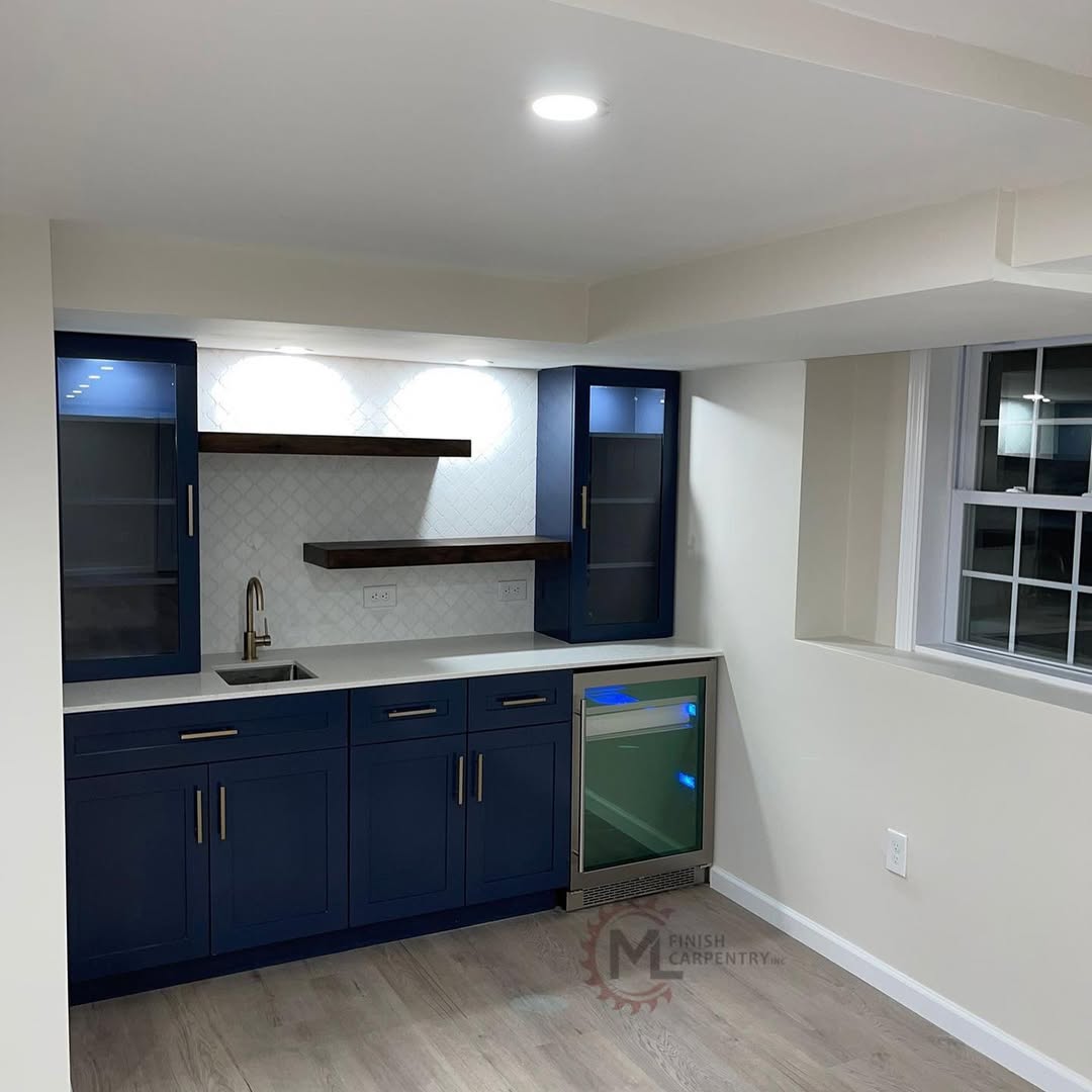 Custom basement wet bar with navy cabinetry, glass-front uppers, floating wood shelves and undercounter refrigeration
