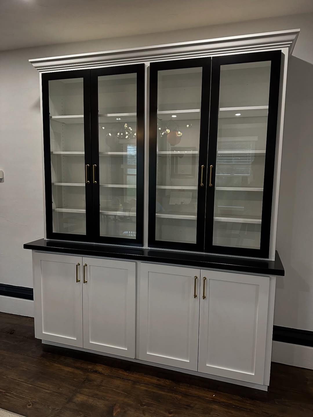Custom display cabinet with black glass-front upper doors, crown moulding and white shaker base cabinets