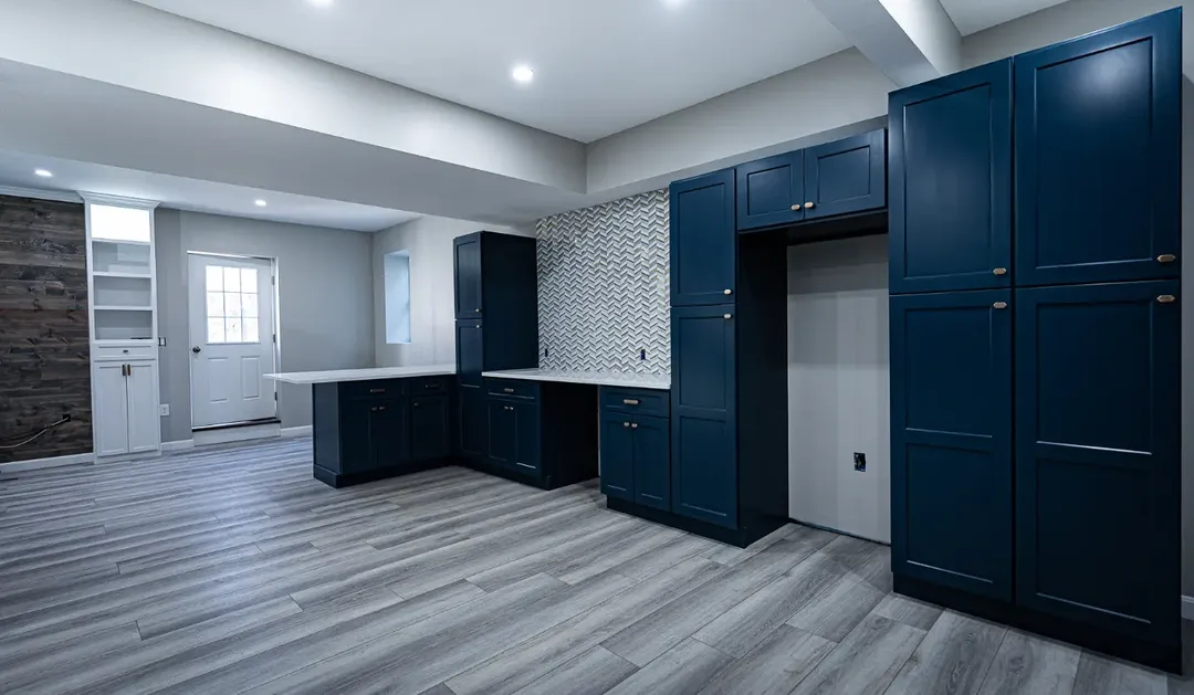 Navy custom basement cabinetry with tall pantry storage, counter run and tile backsplash