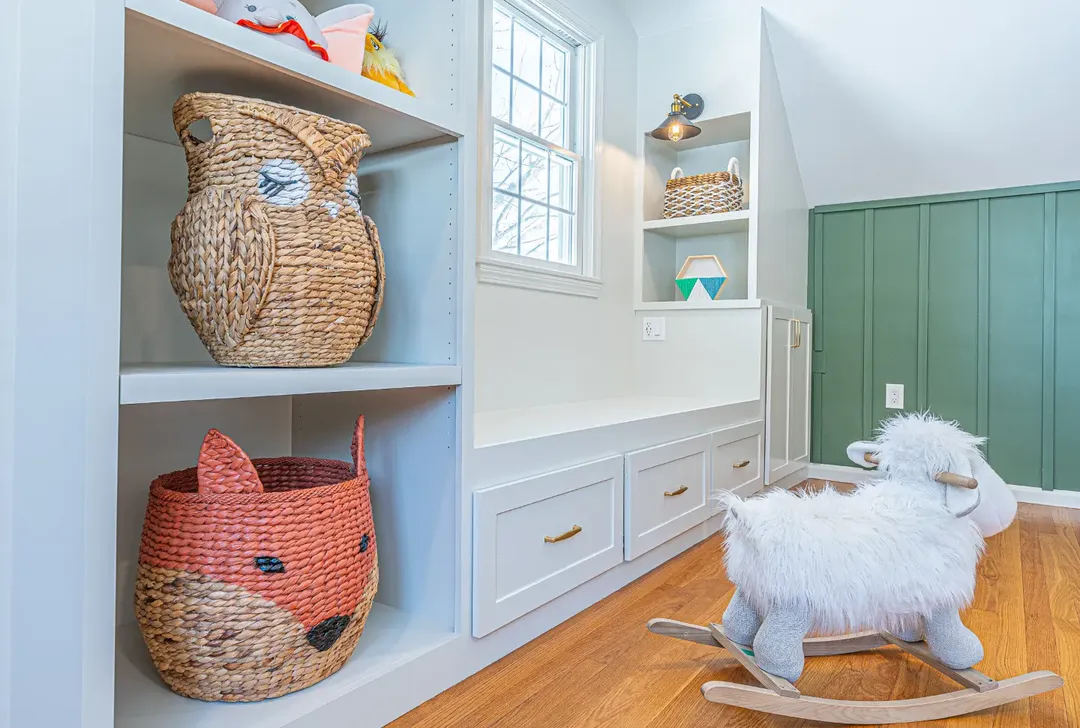 Nursery built-in shelving and bench storage viewed from the side with board-and-batten paneling beyond