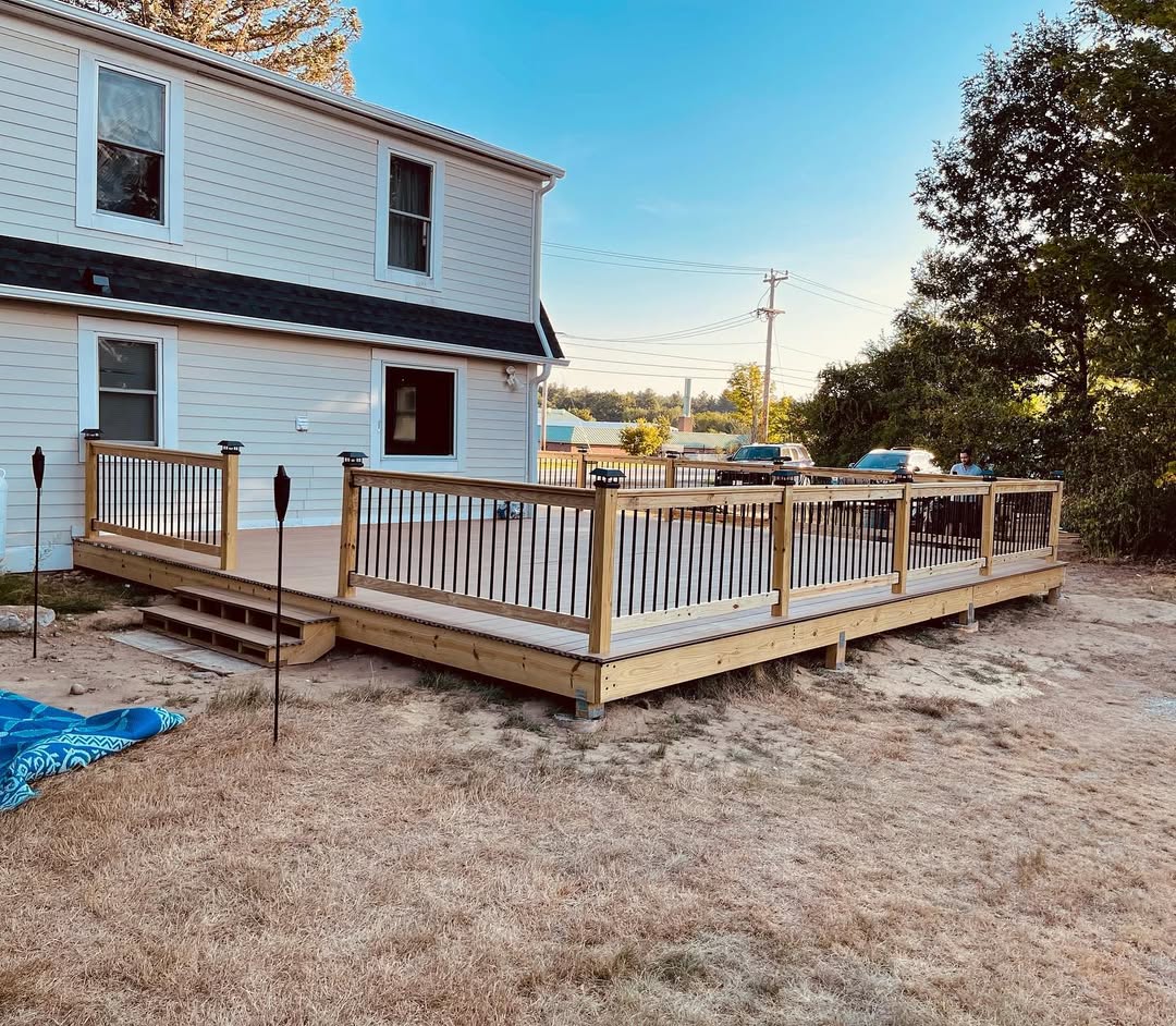 Composite deck with framed railing and steps attached to the rear of a two-storey home