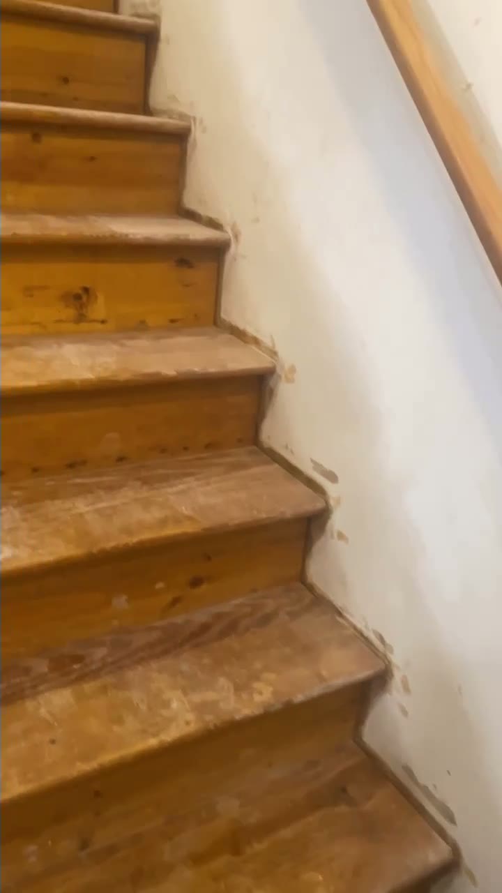 Staircase before refinishing, with worn bare wood treads and risers